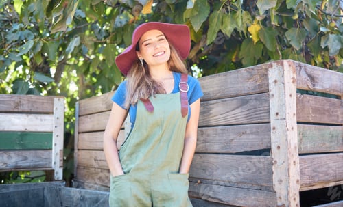 Preview: Portrait of a woman in a straw hat standing under a tree next to a rustic wooden crate. One young h
