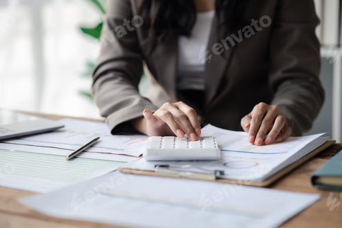 Preview: Businessman using a calculator to calculate numbers on a company's financial documents.
