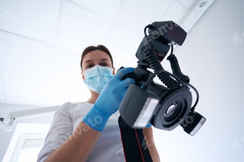 Preview: Professional stomatologist holding photographic device in her hands