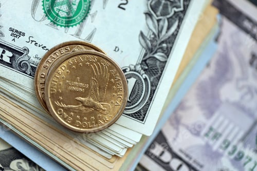 Preview: US dollar money bills and two dollar coins pile. United States coins on banknotes of USD currency