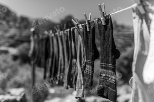 Preview: Greyscale of washed socks on a line in a field surrounded by hills under the sun