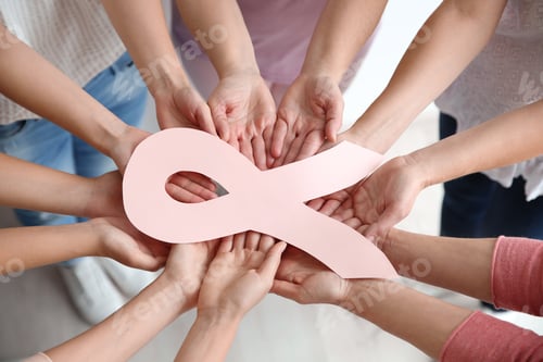 Preview: Women holding pink paper ribbon, above view. Breast cancer awareness concept