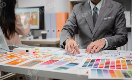 Preview: System Developer Analyzing UX UI Plans in Modern Office Setting with Color Swatches and Wireframes