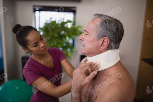 Preview: Female therapist examining neck collar on senior male patient