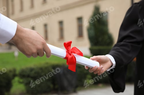 Preview: Student receiving diploma during graduation ceremony outdoors, closeup