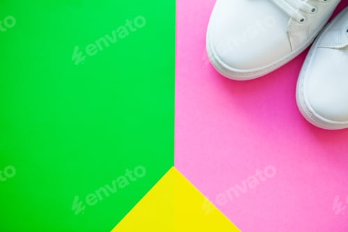 Preview: Pair of new stylish white sneakers on green pink background.