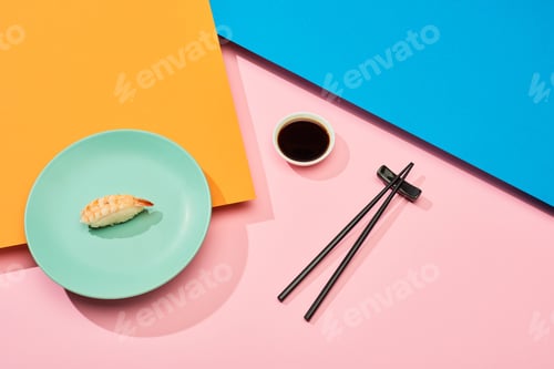 Preview: fresh nigiri with shrimp near soy sauce and chopsticks on blue, pink, orange surface