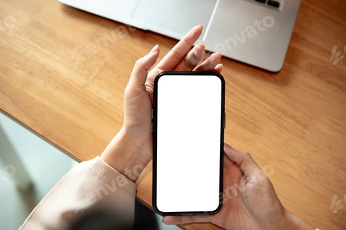 Preview: Close up woman hands holding white screen smartphone aside laptop on wooden table in cafe or library