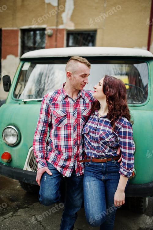 Preview: Stylish couple wear on checkered shirt in love together against old minivan.