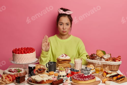 Preview: People, food, dieting concept. Serious brunette woman makes refusal gesture, poses near kitchen tabl