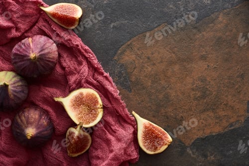 Preview: Top View of Ripe Whole And Cut Delicious Figs on Rustic Red Cloth on Stone Background