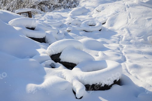 Preview: Used and discarded car tires lie on the side of the road, covered with a thick layer of snow