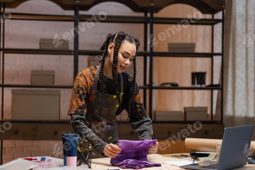 Preview: African american designer holding cloth near devices and equipment in workshop