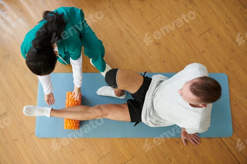 Preview: Woman Assists Man With Foam Roller Exercise At Home