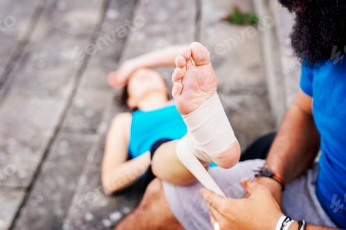 Preview: Man wrapping foot of woman in bandage