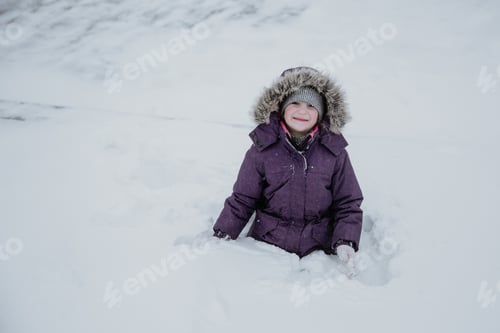 Preview: A young girl in purple jacket and silver hat stands against the white snow background