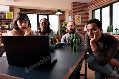 Preview: Anxious multiethnic friends sitting at home while watching suspense movies together on laptop