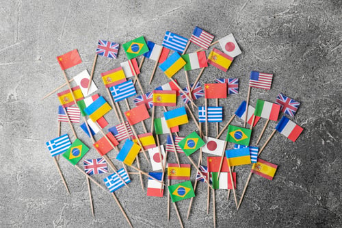 Preview: Many small paper flags of different countries on grey table, flat lay