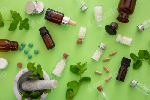 Preview: Homeopathy, globules and herbs on green background