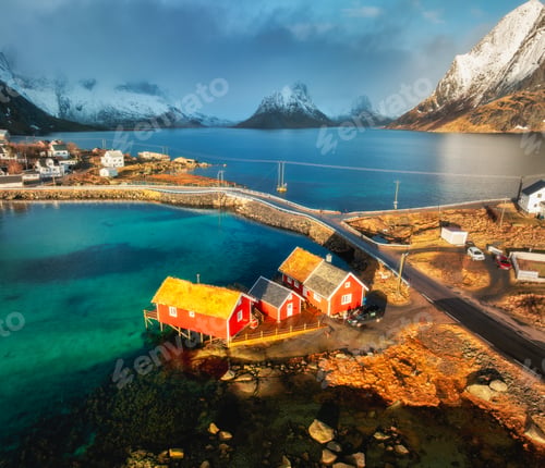 Preview: Aerial view of red rorbuer houses, blue sea and snowy mountains at sunset