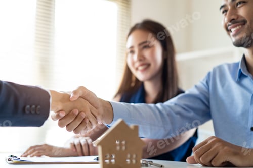 Preview: Young Asian couple making contract with house sale agency shaking hand with female agent.