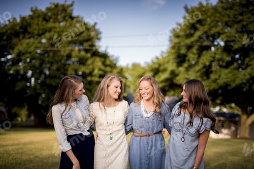 Preview: Group of four female friends hugging each other in the park