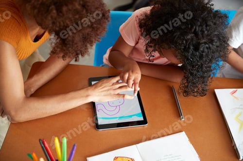 Preview: Elementary School Teacher And Female Pupil Drawing Using Digital Tablet In Classroom
