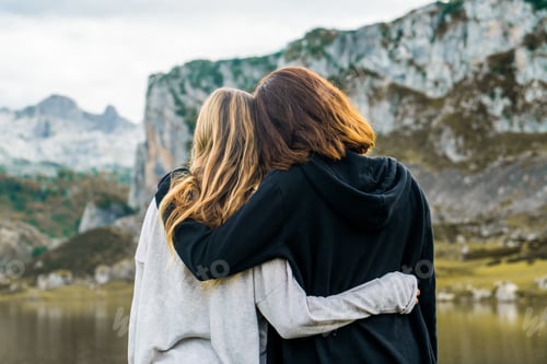 Preview: Rearview shot of two female hugging each other outdoors