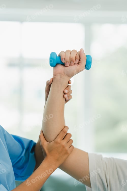 Preview: Physical therapist giving exercise by maintaining dumbbells on the arms and shoulders of a male pati