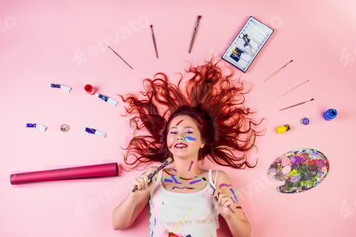 Preview: fun dirty artist painter stains blot from paint on the face lying on the floor next to palette