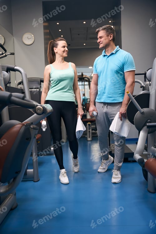 Preview: Cheerful fitness partners communicating before gym workout