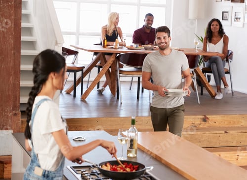 Preview: Friends Prepare And Serve Food For Dinner Party At Home Together