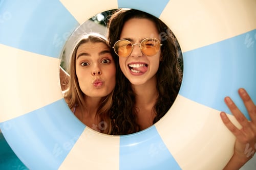 Preview: Funny young women making faces through inflatable pool ring