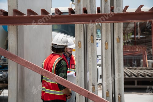 Preview: Engineer or architect with a hardhat examines the schedule on a set of plans.