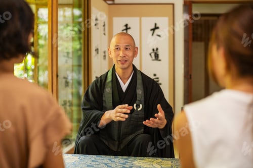 Preview: Two Japanese women and Buddhist priest kneeling in Buddhist temple, talking.