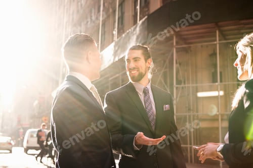 Preview: Happy business people talking while standing by building on sunny day