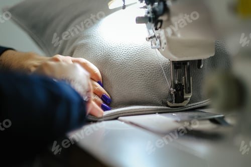 Preview: Closeup of female hands sewing gray leather on a machine
