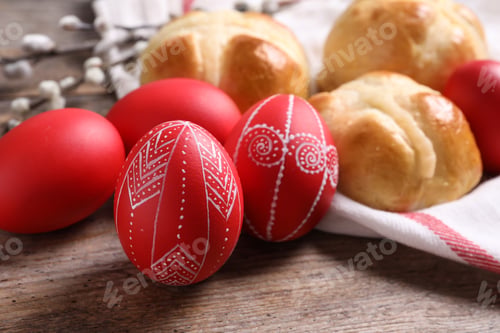 Preview: Red painted Easter eggs and buns on wooden table, closeup