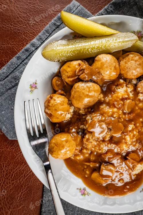 Preview: Chicken meatballs and mushrooms gravy served with groats bulgur and pickled cucumber.