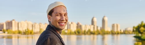 Preview: Stylish young man with tattoos exudes confidence by the lakeside in the vibrant city