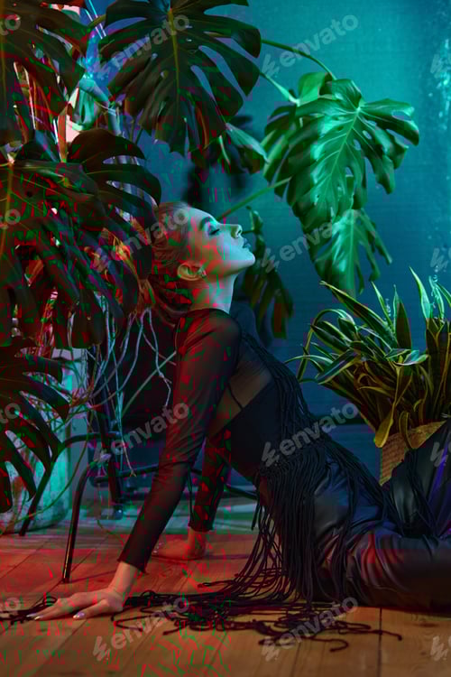 Preview: Young woman surrounded by vibrant tropical plants, wearing black leather outfit and long-sleeved