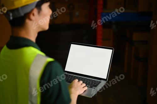 Preview: Cropped shot of male warehouse worker using laptop aisle between rows.