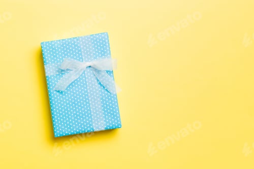 Preview: wrapped Christmas or other holiday handmade present in paper with white ribbon
