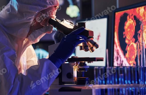 Preview: Scientist in white protective uniform near displays with data works with coronavirus and blood tubes