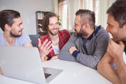 Preview: Cheerful men sitting in front of the laptop