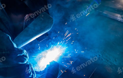 Preview: Welder welding metal with argon arc welding machine and has welding sparks. A man wears welding mask