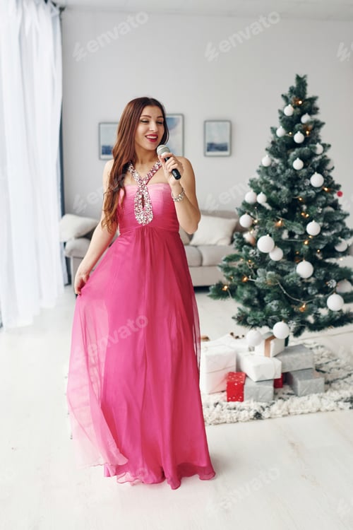 Preview: Beautiful woman in pink dress singing indoors at New year party