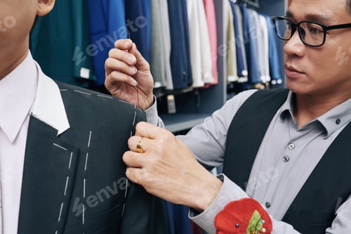 Preview: Focused tailor working with sewing needle in studio