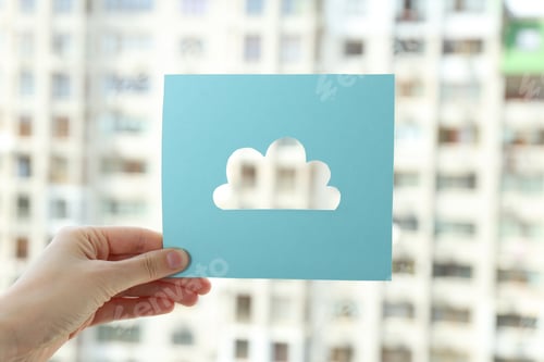 Preview: The cloud is cut out of paper in the hand against the background of the city