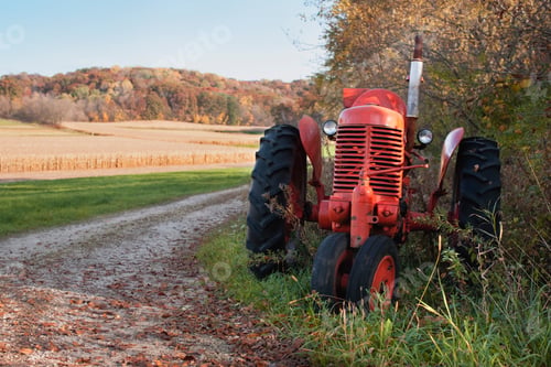 Preview: Old red tractor sits alongside a dirt road by corn fields and hills in autumn color